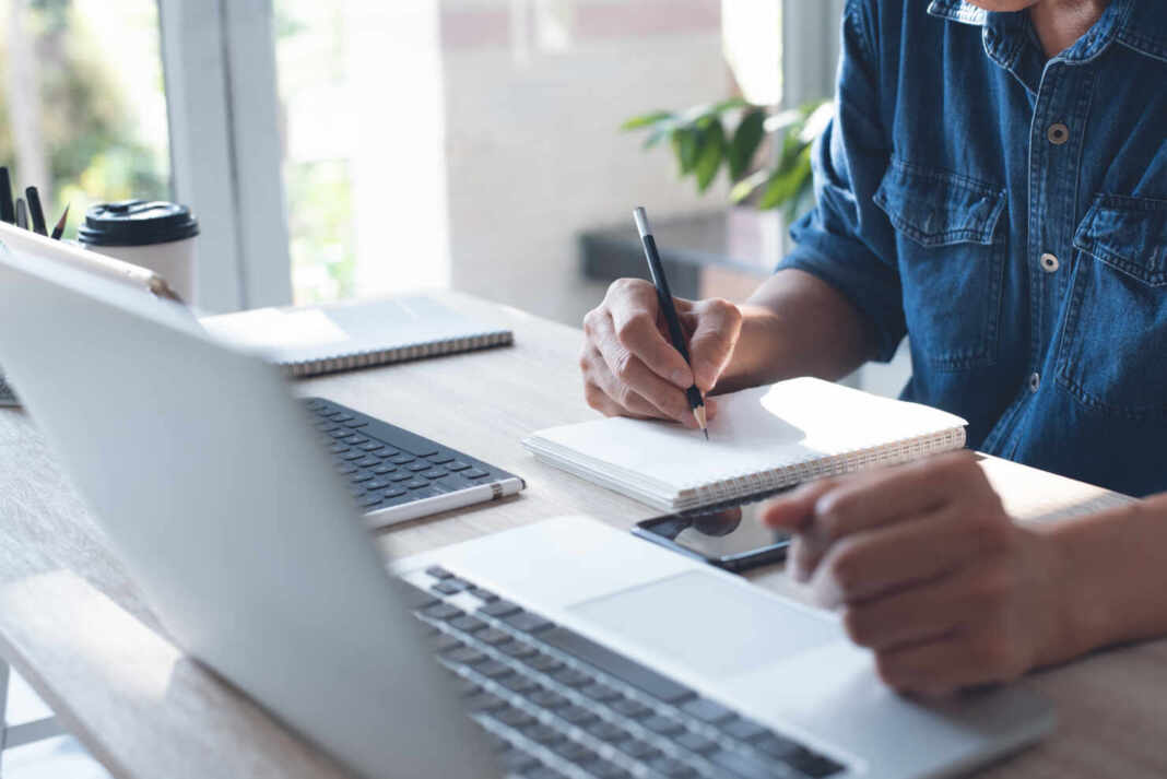 Estudiante tomando notas frente a su laptop durante un curso gratuito de inteligencia artificial