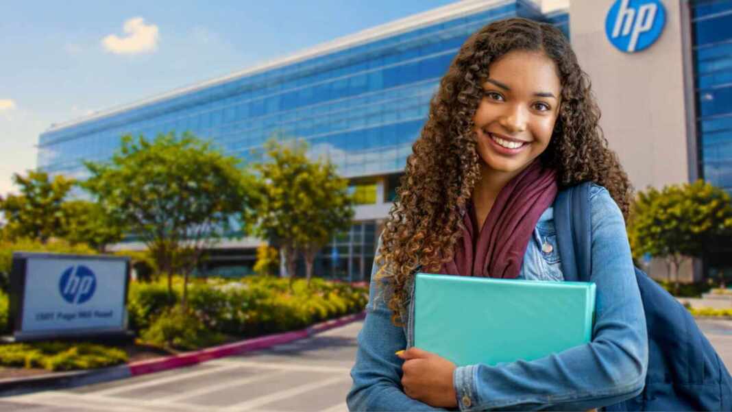Estudiante sonriente con laptop frente a un edificio de HP, curso gratis de marketing en redes sociales