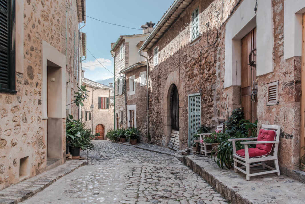 Calle empedrada de un pueblo europeo con casas tradicionales, ejemplo de comunidades que pagan por mudarte