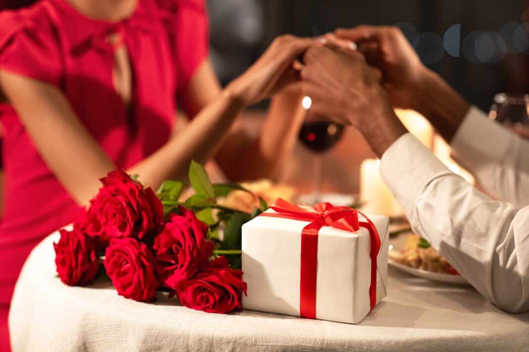 Pareja con rosas y un regalo en una cena de Amor y Amistad