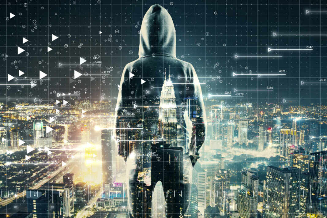 Persona de espaldas frente a pantallas de computadora de noche