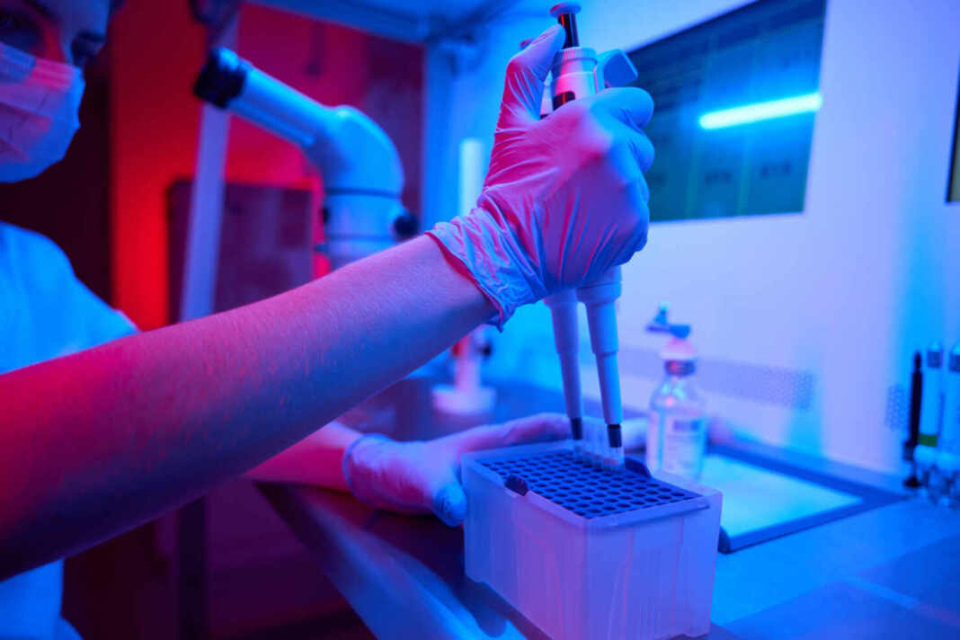 Técnica de laboratorio usando una pipeta para preparar biomaterial
