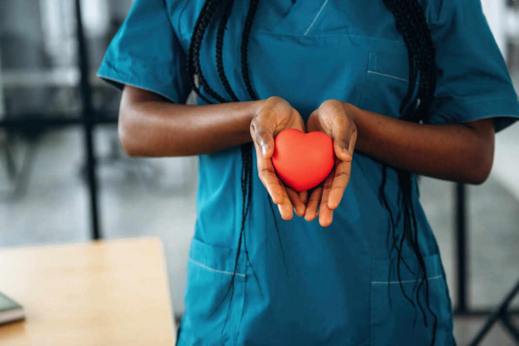 Manos de una médica sosteniendo un modelo de corazón rojo