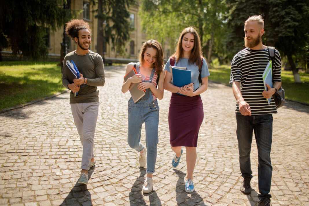 Estudiantes universitarios caminando por el campus en un día soleado