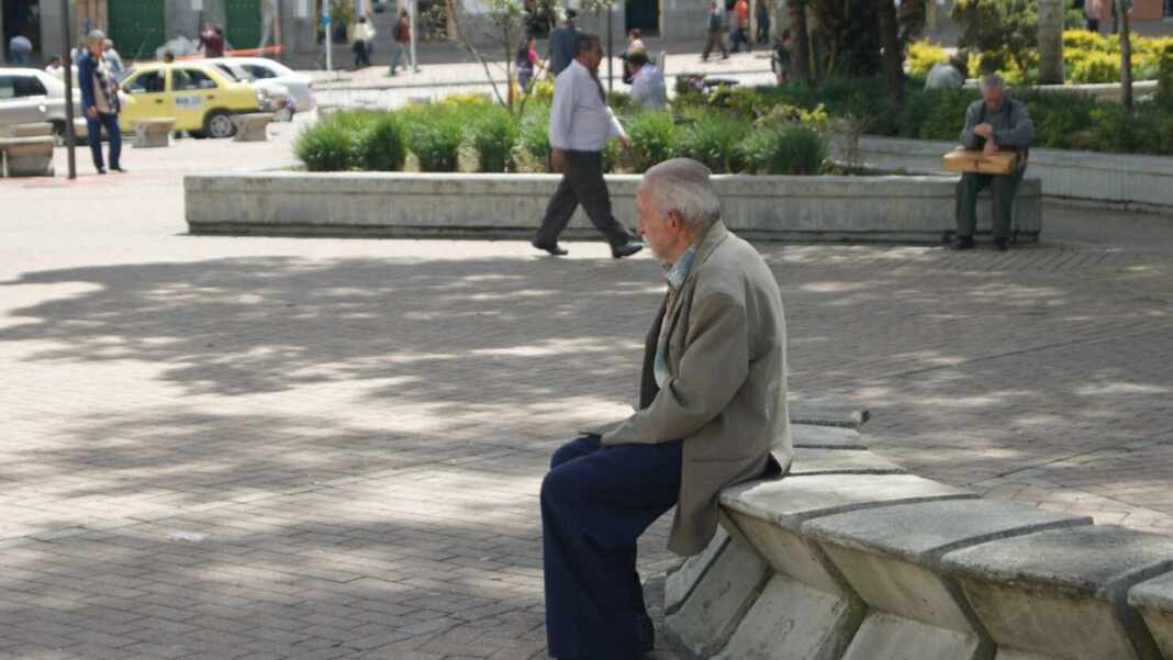 Hombre mayor sentado solo en una banca de un parque
