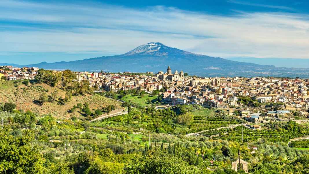 El volcán Etna visto desde un pueblo y campos de cultivo en Sicilia, Italia