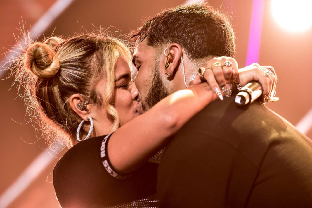 Anuel AA y Karol G besándose en el escenario.