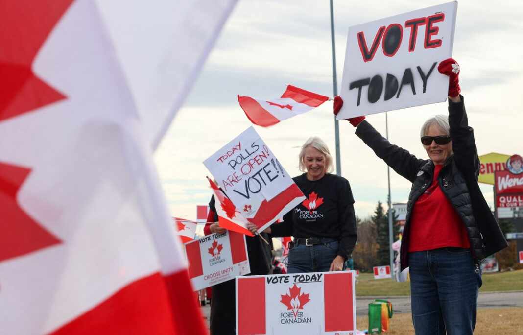 Simpatizantes de Forever Canadian con banderas de Canadá y carteles que llaman a votar durante la jornada del referendo en Alberta