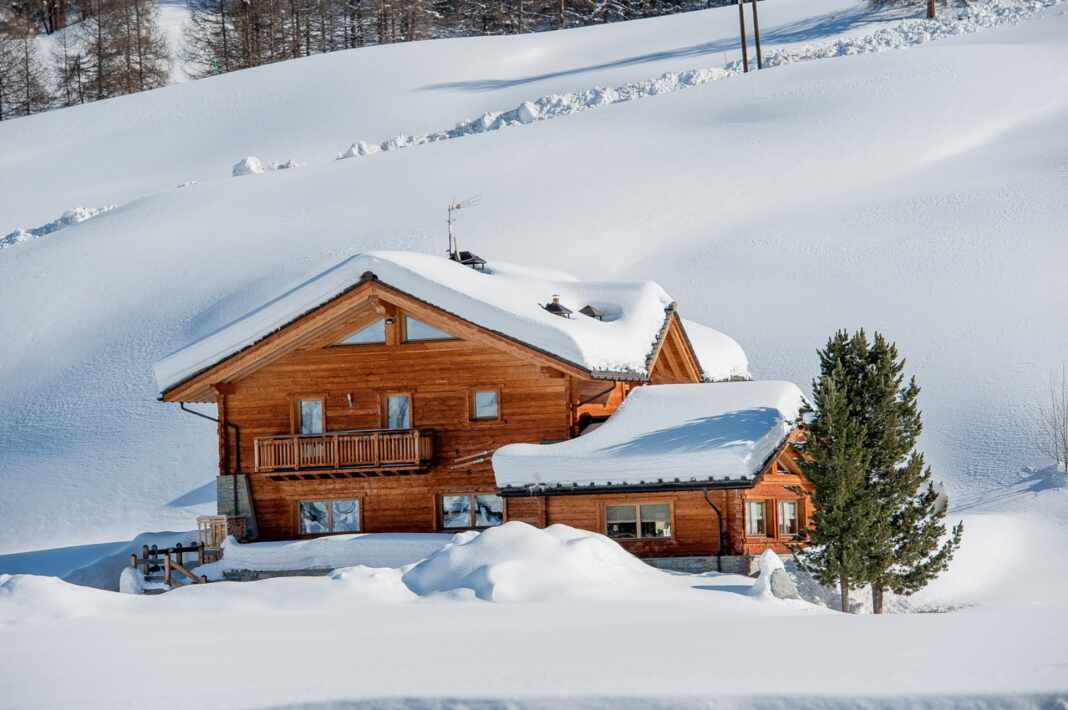 Chalet de madera cubierto de nieve en los Alpes