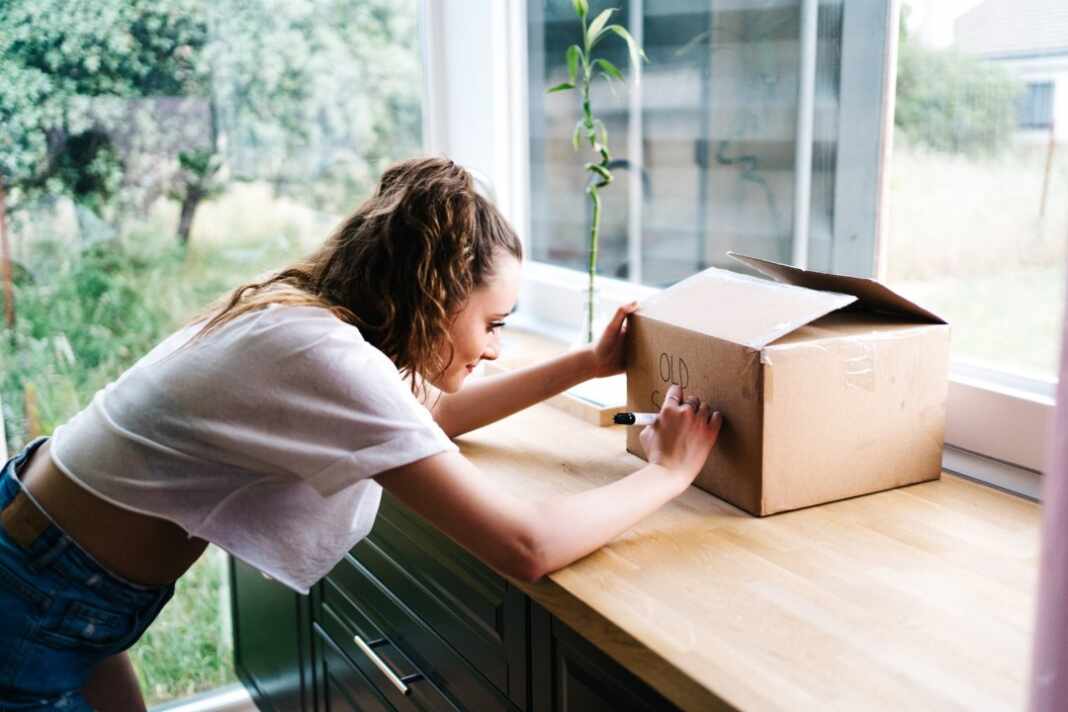 Mujer guarda objetos en una caja de cartón, como en las devoluciones de Amazon