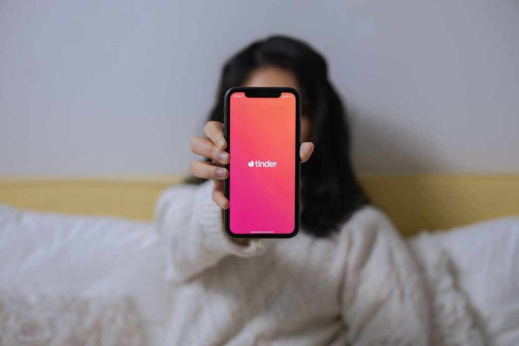 Mujer mostrando la app de Tinder en su celular, la nueva app del estafador de Tinder