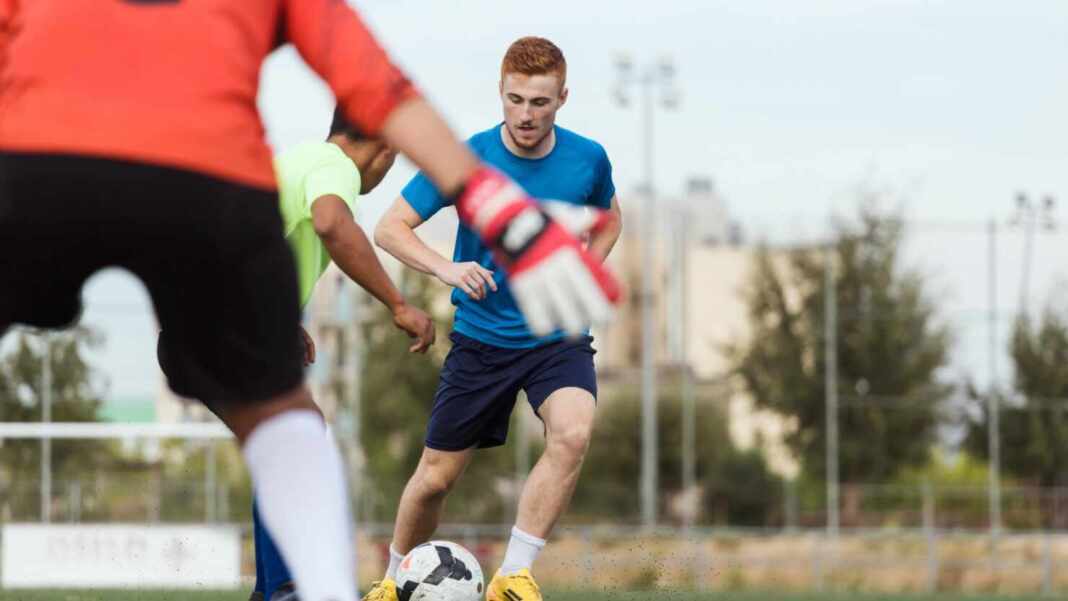 Jugadores de fútbol disputan el balón frente al portero en un entrenamiento