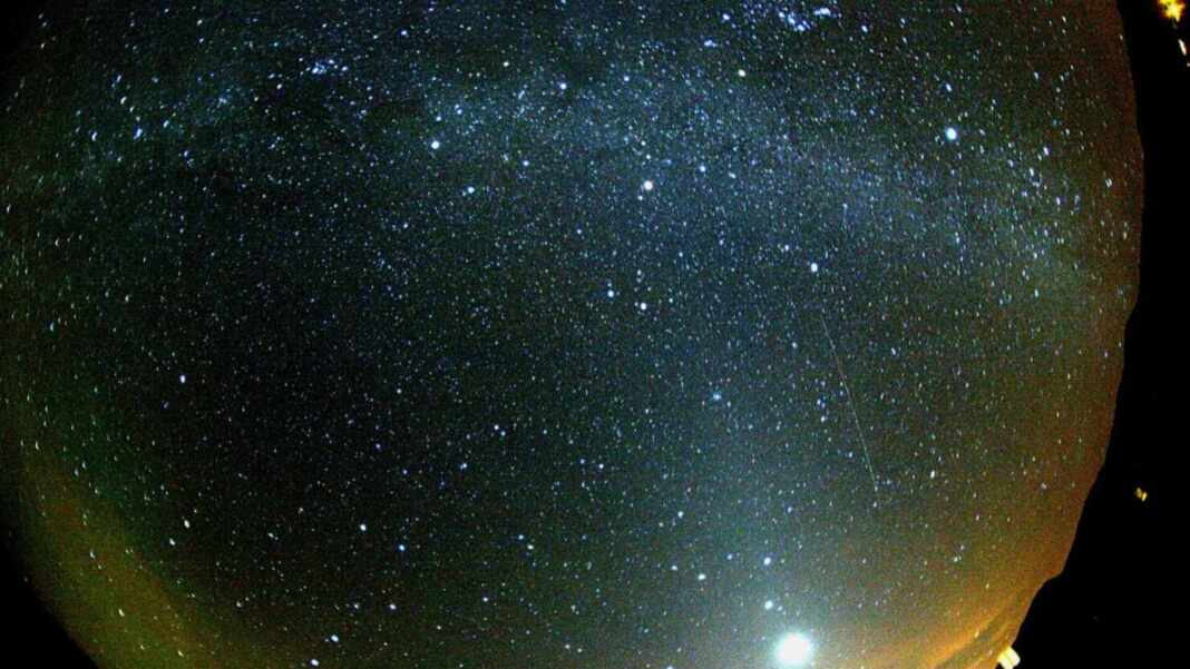 Meteoro verde y rojo de la lluvia de estrellas Oriónidas bajo la Vía Láctea, junto al planeta Venus