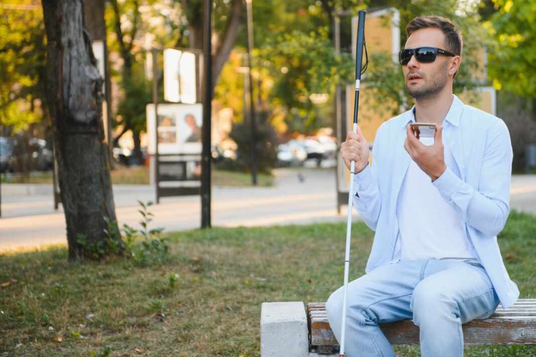 Hombre ciego con bastón sentado en un parque, perfil de pacientes de la terapia génica