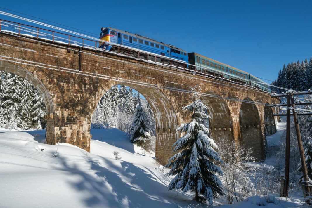 Tren cruza un puente de piedra nevado en invierno, paisaje como el que recorre el nuevo tren nocturno